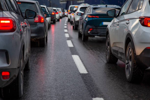 Traffic jam with a row of cars on a highway during rush hour in the evening after work. red brake lights of stopped cars on the background of wet asphalt with white lanes at sunset